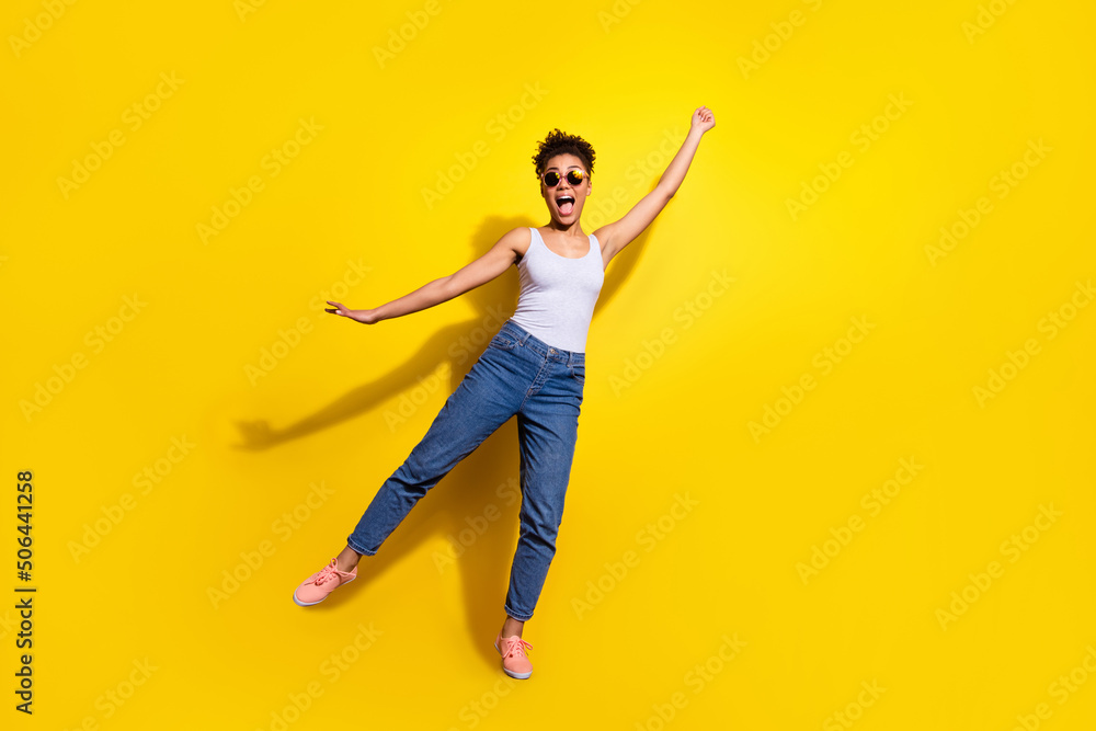 Full body photo of funky overjoyed girl raise arm empty space hold umbrella isolated on yellow color background