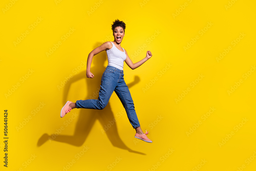 Full size photo of energetic active girl hurry rush fast jumping isolated on yellow color background