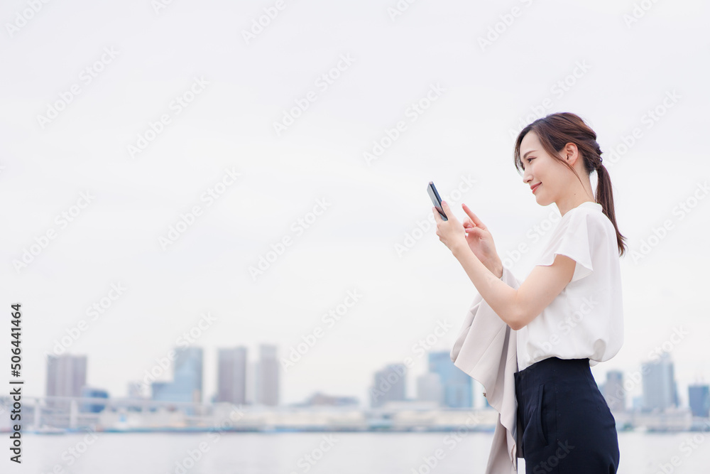 屋外でメッセージを打つ若い女性