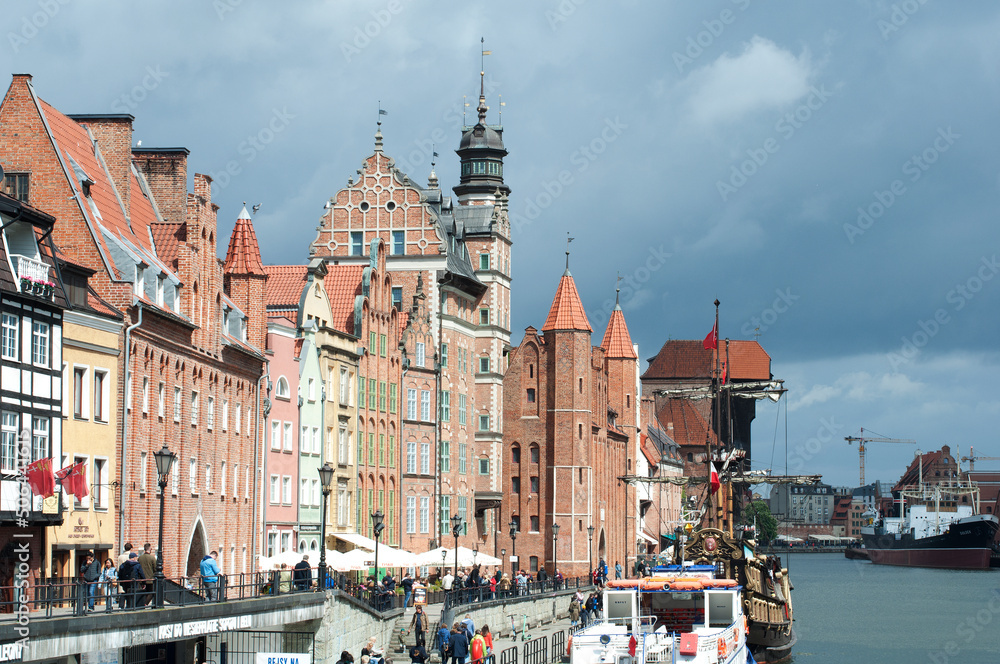 Obraz premium Motlawa River Embankment in Gdansk. View of the river with ships, the old town and the crane gate Zhurav. Historical and tourist attractions in Poland