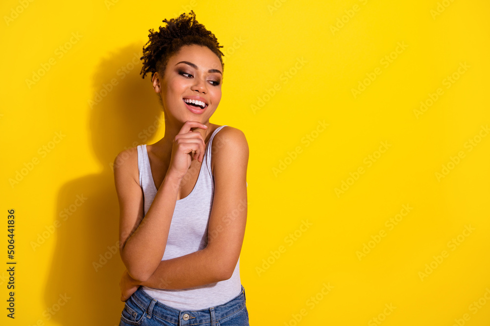 Photo of gorgeous positive lady arm touch chin look interested empty space blank isolated on yellow color background Photo of gorgeous positive lady arm touch chin look interested empty space blank isolated on yellow color background