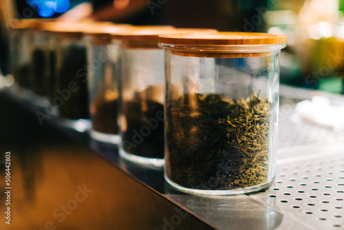 Different types of tea in a glass jars in a bar counter, close up.