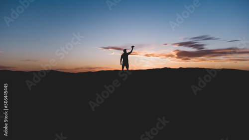 Silueta de un hombre con la c  mara  en lo alto de la monta  a  con un bonito atardecer. Fotograf  a horizontal con espacio para texto.