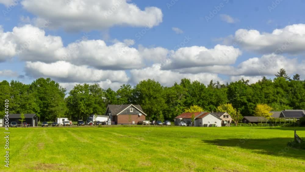 Time lapse of busy farms with green meadows in the foreground and clouds passing in the sky - slow zoom in Time lapse of busy farms with green meadows in the foreground and clouds passing in the sky - slow zoom in