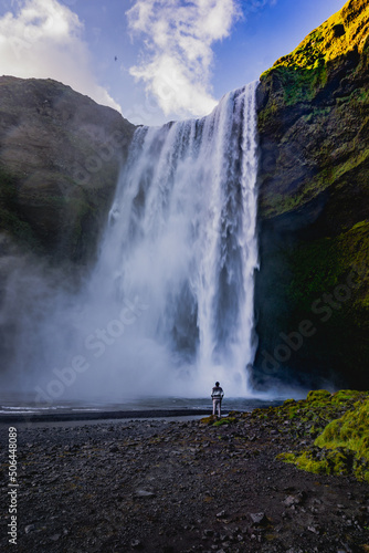 Skogafoss waterfall in Iceland at sunset with someone in front of it