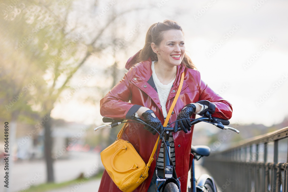 Obraz premium smiling stylish woman in red rain coat outdoors in city