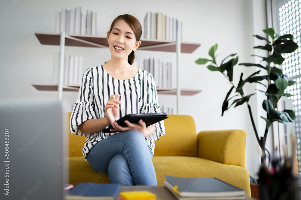 A photo of a bright Asian business woman working home in room. The idea is Work form Home Finance Marketing Bright Portrait Simple Sell online at home Chat with customers via the Internet with laptop A photo of a bright Asian business woman working home in room. The idea is Work form Home Finance Marketing Bright Portrait Simple Sell online at home Chat with customers via the Internet with laptop
