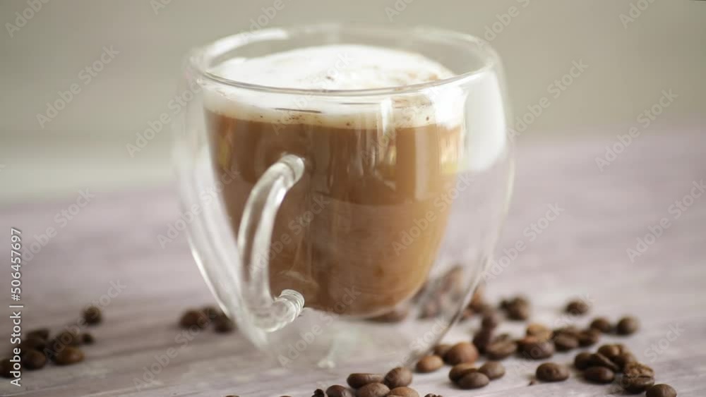 A cup of hot coffee with milk with coffee beans, on a wooden table. A cup of hot coffee with milk with coffee beans, on a wooden table.