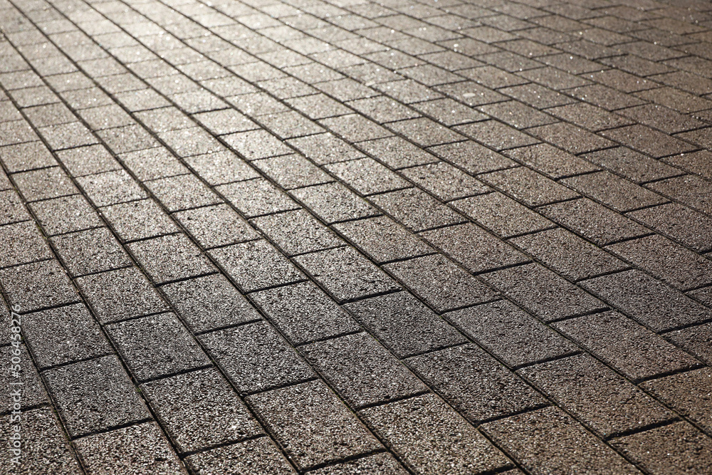 Stone pavement texture, cobbled street in sunlight. Road from tiles