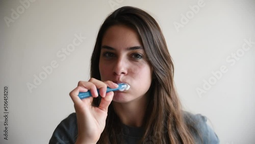 Young beautiful woman brushes her teeth with a toothbrush in the morning. Self loved female preparing and doing morning routine self hygiene before she go to the work. Washing teeth woman