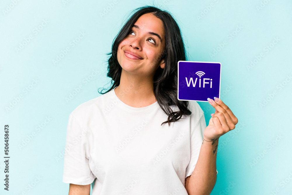 Young hispanic woman holding wifi placard isolated on yellow background dreaming of achieving goals and purposes Young hispanic woman holding wifi placard isolated on yellow background dreaming of achieving goals and purposes