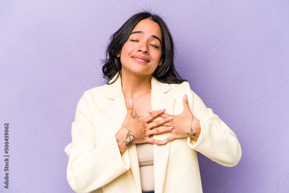 Young hispanic woman isolated on purple background has friendly expression, pressing palm to chest. Love concept. Young hispanic woman isolated on purple background has friendly expression, pressing palm to chest. Love concept.