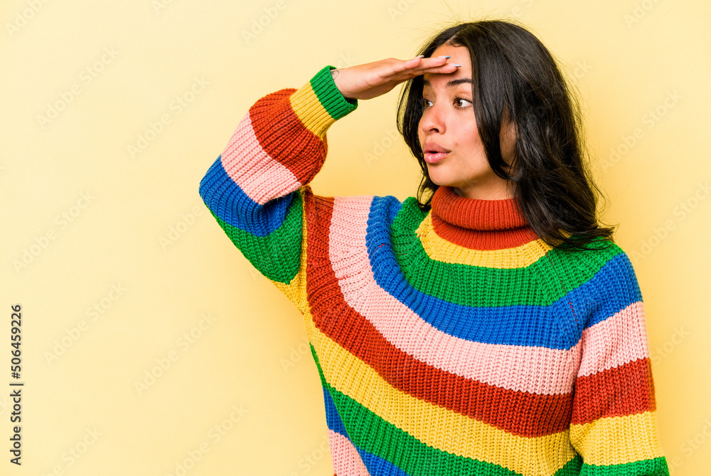 Young hispanic woman isolated on yellow background looking far away keeping hand on forehead. Young hispanic woman isolated on yellow background looking far away keeping hand on forehead.