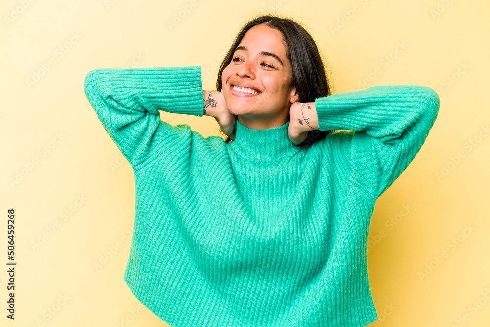 Young hispanic woman isolated on yellow background feeling confident, with hands behind the head. Young hispanic woman isolated on yellow background feeling confident, with hands behind the head.
