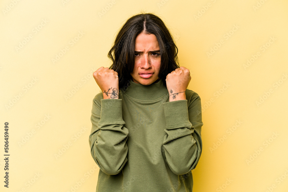 Young hispanic woman isolated on yellow background upset screaming with tense hands. Young hispanic woman isolated on yellow background upset screaming with tense hands.