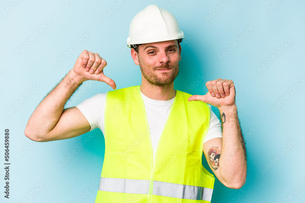 Young laborer caucasian man isolated on blue background feels proud and self confident, example to follow. Young laborer caucasian man isolated on blue background feels proud and self confident, example to follow.