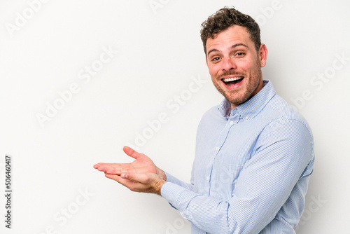 Young caucasian man isolated on white background holding a copy space on a palm.