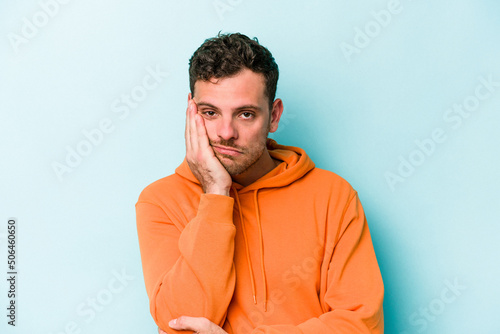 Young caucasian man isolated on blue background who is bored, fatigued and need a relax day. © Asier