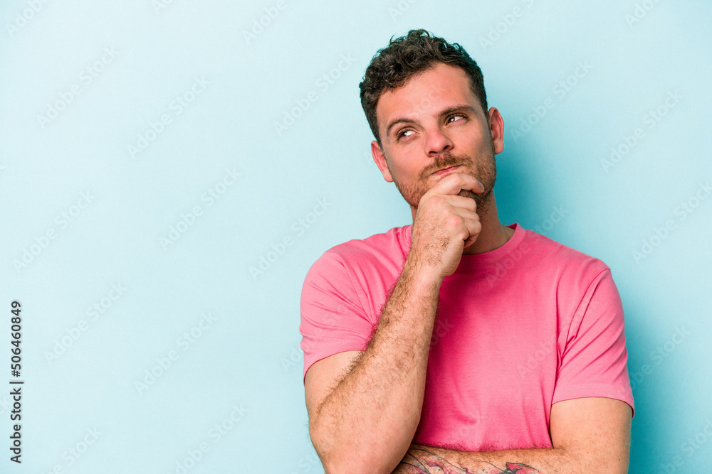 Young caucasian man isolated on blue background looking sideways with doubtful and skeptical expression. Young caucasian man isolated on blue background looking sideways with doubtful and skeptical expression.