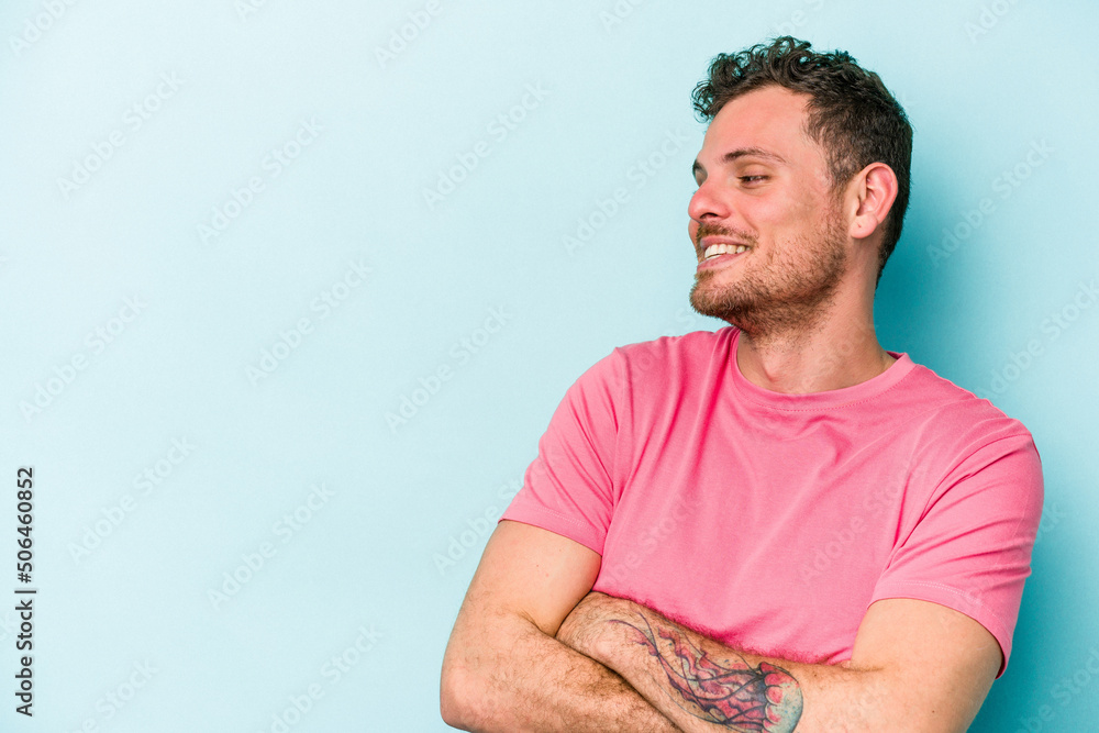 Young caucasian man isolated on blue background smiling confident with crossed arms. Young caucasian man isolated on blue background smiling confident with crossed arms.