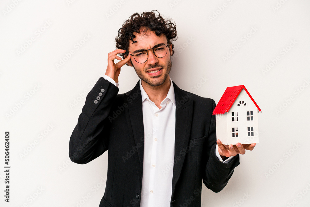Young caucasian business man holding a toy house isolated on white background showing a disappointment gesture with forefinger. Young caucasian business man holding a toy house isolated on white background showing a disappointment gesture with forefinger.