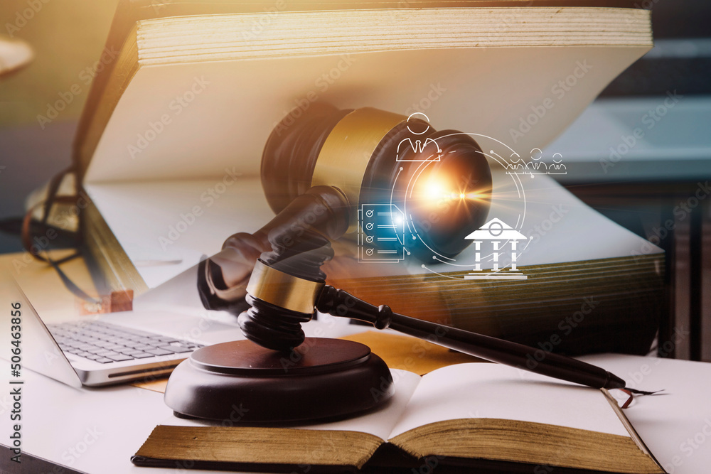 Justice and law concept.Male judge in a courtroom with the gavel, working with, computer and docking keyboard, eyeglasses, on table in morning light Justice and law concept.Male judge in a courtroom with the gavel, working with, computer and docking keyboard, eyeglasses, on table in morning light