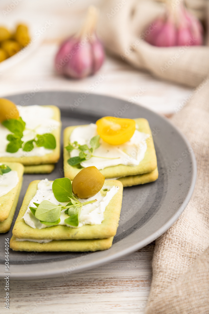 Green cracker sandwiches with cream cheese and cherry tomatoes on white wooden background. side view, selective focus. Green cracker sandwiches with cream cheese and cherry tomatoes on white wooden background. side view, selective focus.