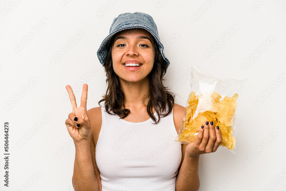 Young hispanic woman holding a bag of chips isolated on white background showing number two with fingers. Young hispanic woman holding a bag of chips isolated on white background showing number two with fingers.