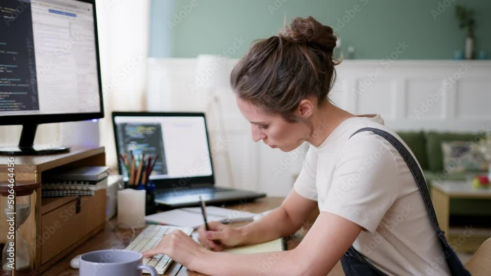 intent female freelancer works on computer in home office, types on laptop keyboard. young focused student on distance education using computer, makes notes. looks serious during webinar intent female freelancer works on computer in home office, types on laptop keyboard. young focused student on distance education using computer, makes notes. looks serious during webinar