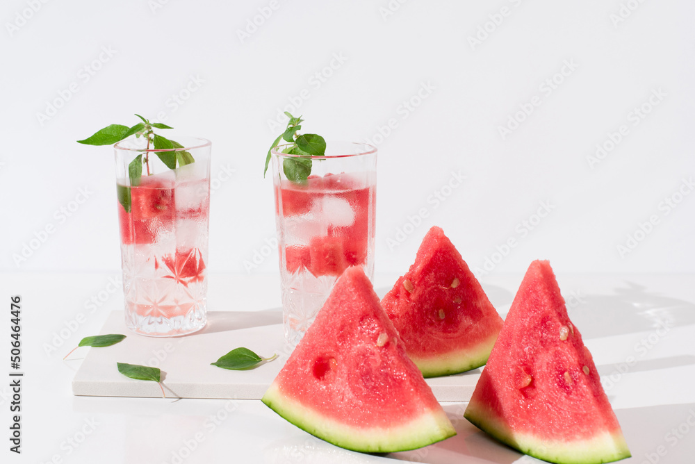 Dos vasos de zumo de sandía con trozos de sandia y hielo sobre fondo claro Dos vasos de zumo de sandía con trozos de sandia y hielo sobre fondo claro