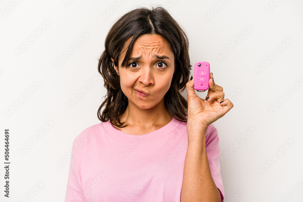 Young hispanic woman holding car keys isolated on white background confused, feels doubtful and unsure. Young hispanic woman holding car keys isolated on white background confused, feels doubtful and unsure.