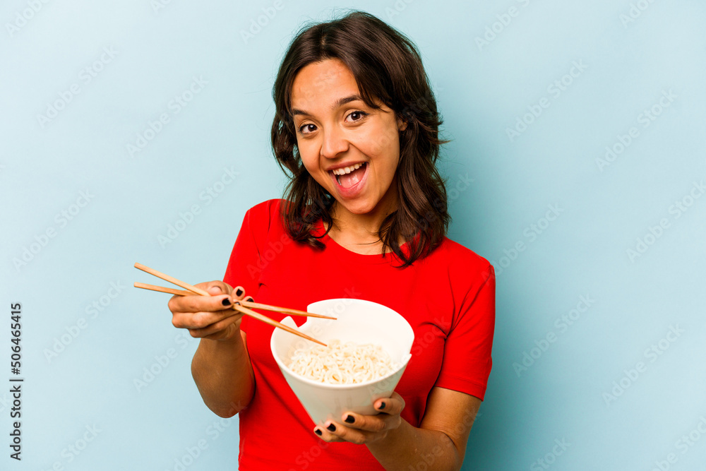 Young hispanic woman eating noodles isolated on blue background Young hispanic woman eating noodles isolated on blue background