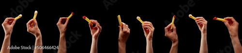 Some Hands with french fries in a row with mayonnaise and ketchup on black background