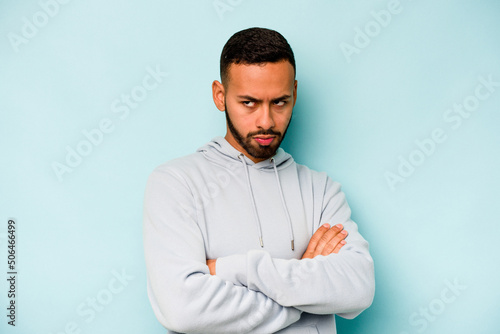 Young hispanic man isolated on blue background tired of a repetitive task.
