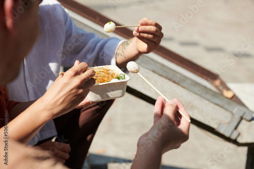 Closeup image of friends enjoying street food with boiled quail eggs