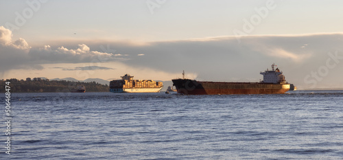 Big Container Ship parked in Burrard Inlet on the West Coast of Pacific Ocean. Colorful cloudy sunset sky. Vancouver, British Columbia, Canada. Panorama