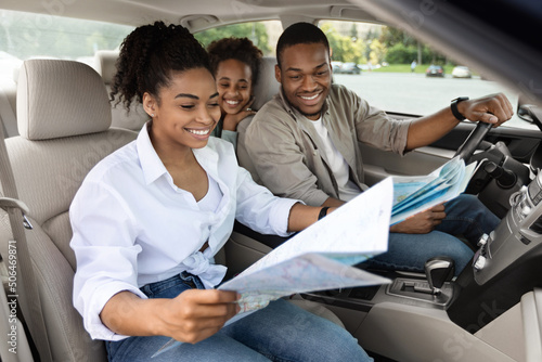 Happy Black Family Sitting In Car Looking At Road Map