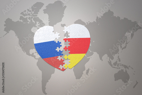 puzzle heart with the national flag of russia and south ossetia on a world map background. Concept.