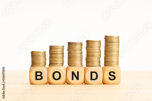 Bonds word on wood block with growing stacked coins. Bonds increasing concept. Copy space