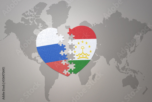 puzzle heart with the national flag of russia and tajikistan on a world map background. Concept.