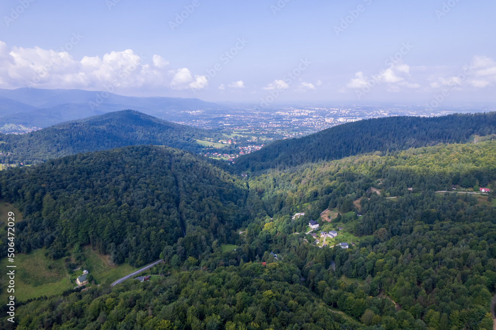 Mountains and forests in the vicinity of Bielsko-Biala. Sunny weather and green trees. The road in the middle of the forest.
