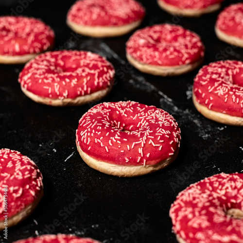 Set of dark, pink and white chocolate donuts on dark background, top view. Bakery, baking concept.