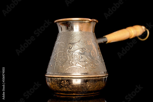 One Turkish Cezve coffee pot with wooden handle, closeup isolated on black background.