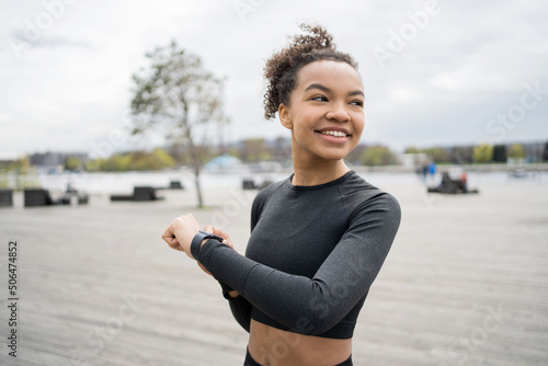 A smart watch with a pulse and a cardio machine is used by a female trainer who trains outside in sports clothes.