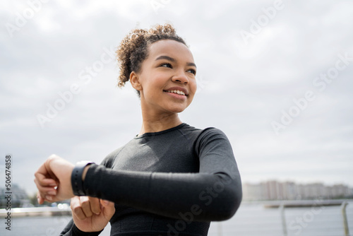 Uses a pulse and cardio smartwatch, a female trainer training outside in sportswear.