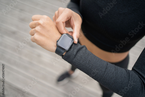 Smart watch with pulse and cardio machine, a female trainer trains outside in sportswear.