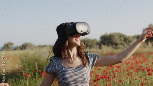 Young girl has fun with virtual reality in a field of red flowers photo