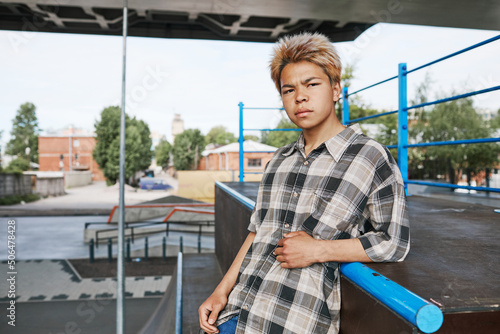 Fotografie, Tablou Waist up portrait of teenage boy looking at camera in skatepark outdoors in urba