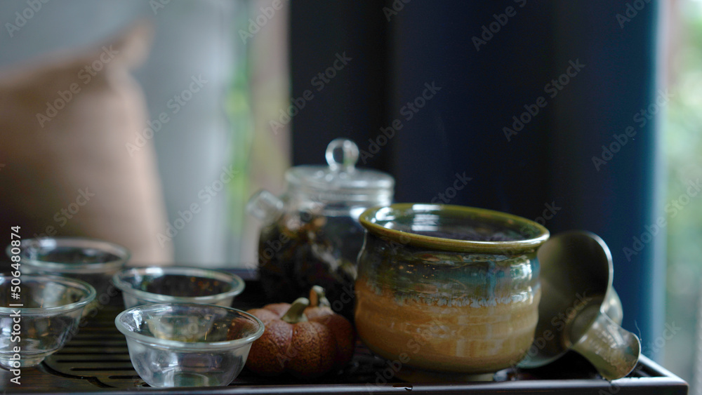 Traditional tea set tray with modern transparent pot and clear small cup in cozy Chinese room. Natural healthy hot clear drink with dried leaves give good aroma and relax for drink. Traditional tea set tray with modern transparent pot and clear small cup in cozy Chinese room. Natural healthy hot clear drink with dried leaves give good aroma and relax for drink.