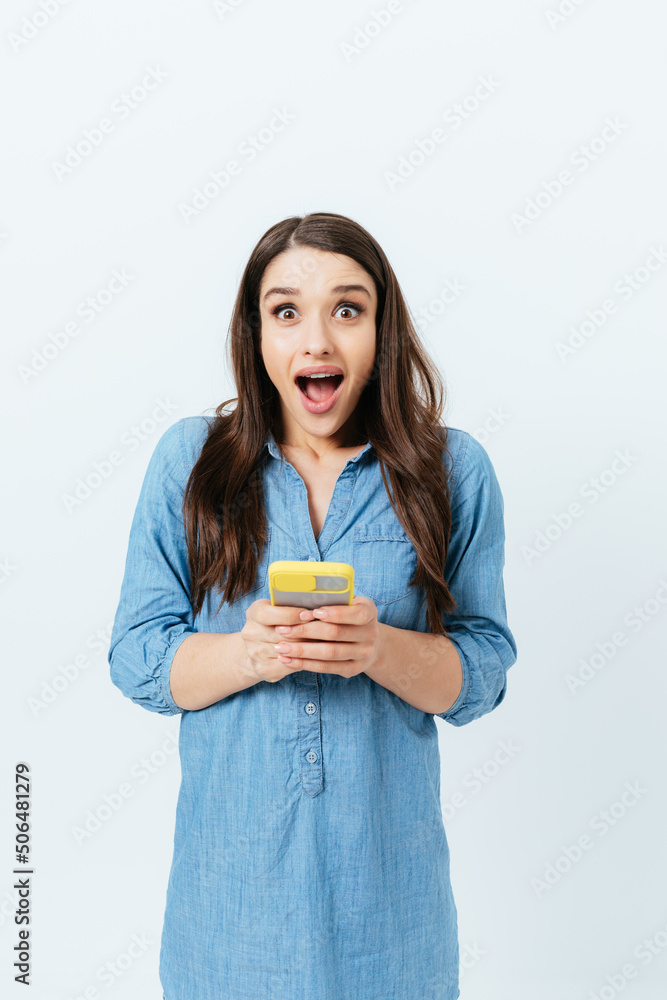 Surprised young brunette woman holding smartphone Surprised young brunette woman holding smartphone